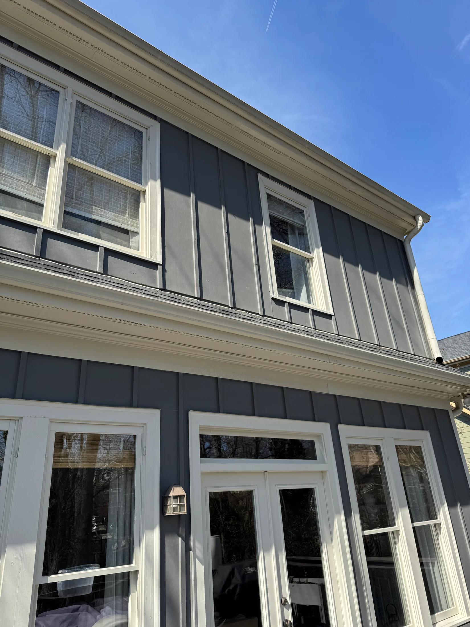 Gray two-story house exterior with white-framed windows, trim and rear doors.